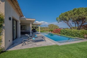 A modern house with a swimming pool, outdoor seating, and a well-maintained garden.