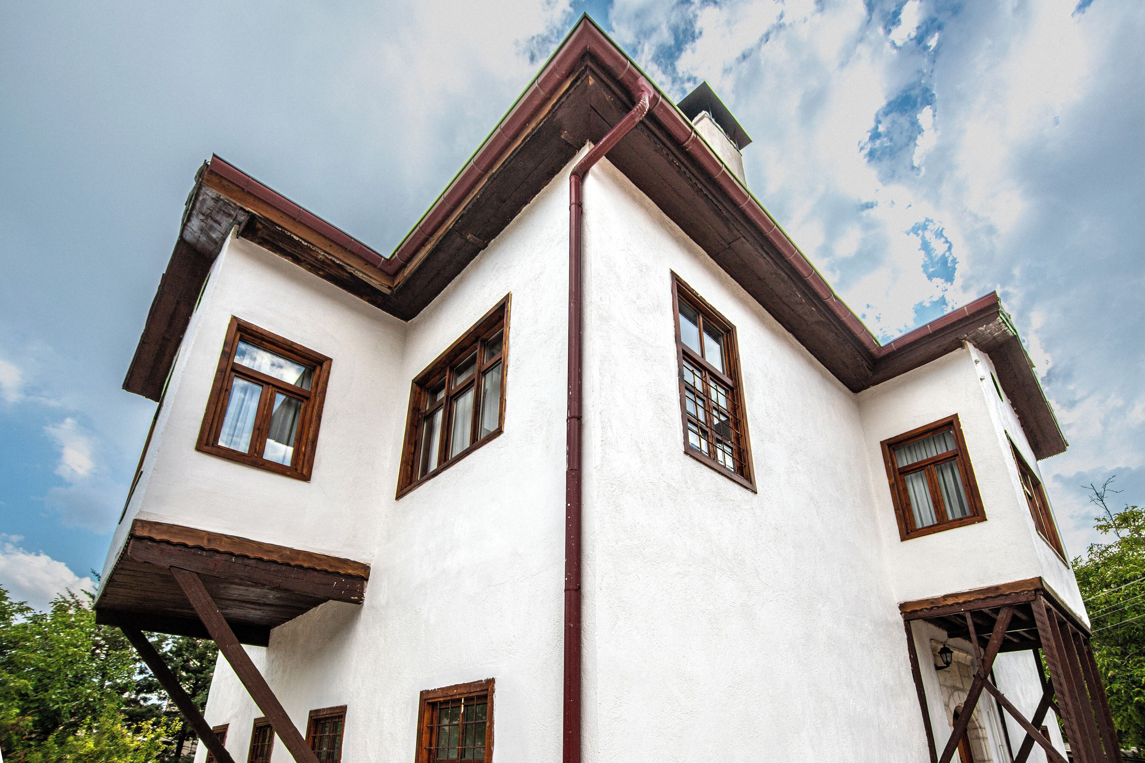 A white building with brown window frames and a red roof.