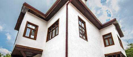 A white building with brown window frames and a red roof.
