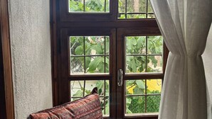 A room with a large wooden door with glass panels, a patterned cushion, and a white curtain. - Marassa Konak Otel (Ermenek)
