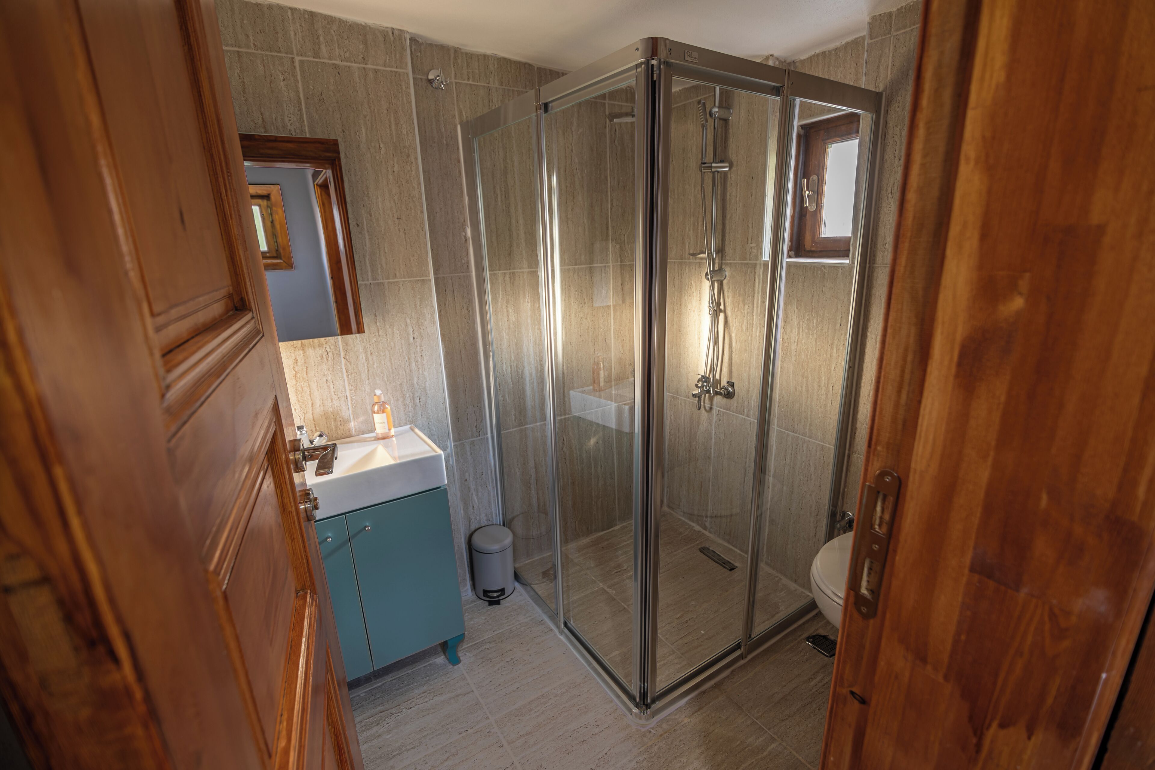 A bathroom with a glass-enclosed shower, a wooden vanity, and a toilet.