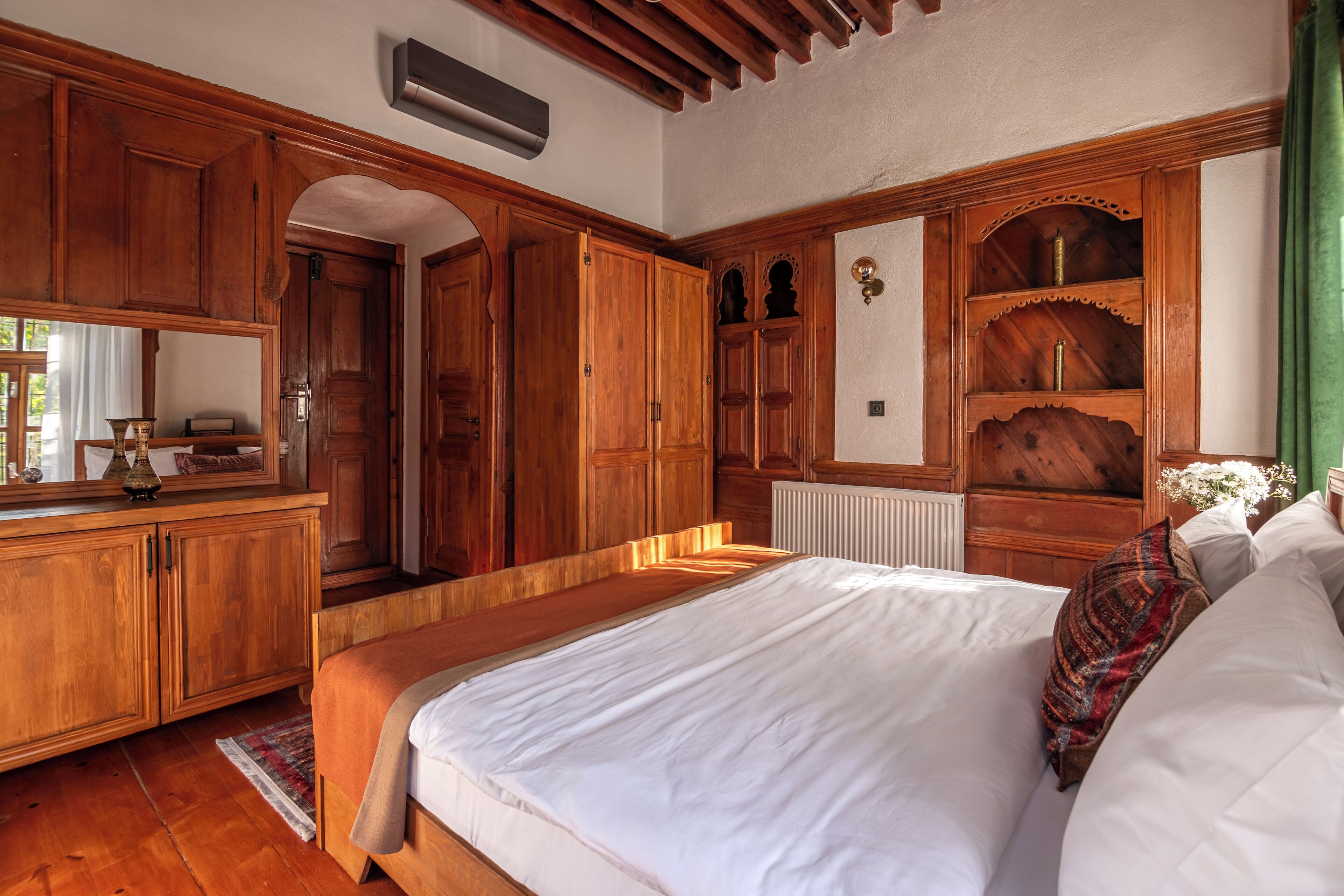 Een slaapkamer met houten meubels, een bed met witte lakens en een radiator.
