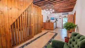 A wooden interior with a staircase, a reception desk, and a green sofa. - Marassa Konak Otel (Ermenek)