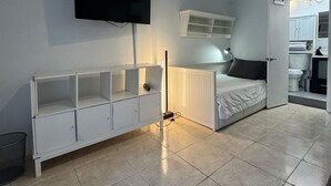 Un dormitorio con cama, televisión, mesita de noche y armario.