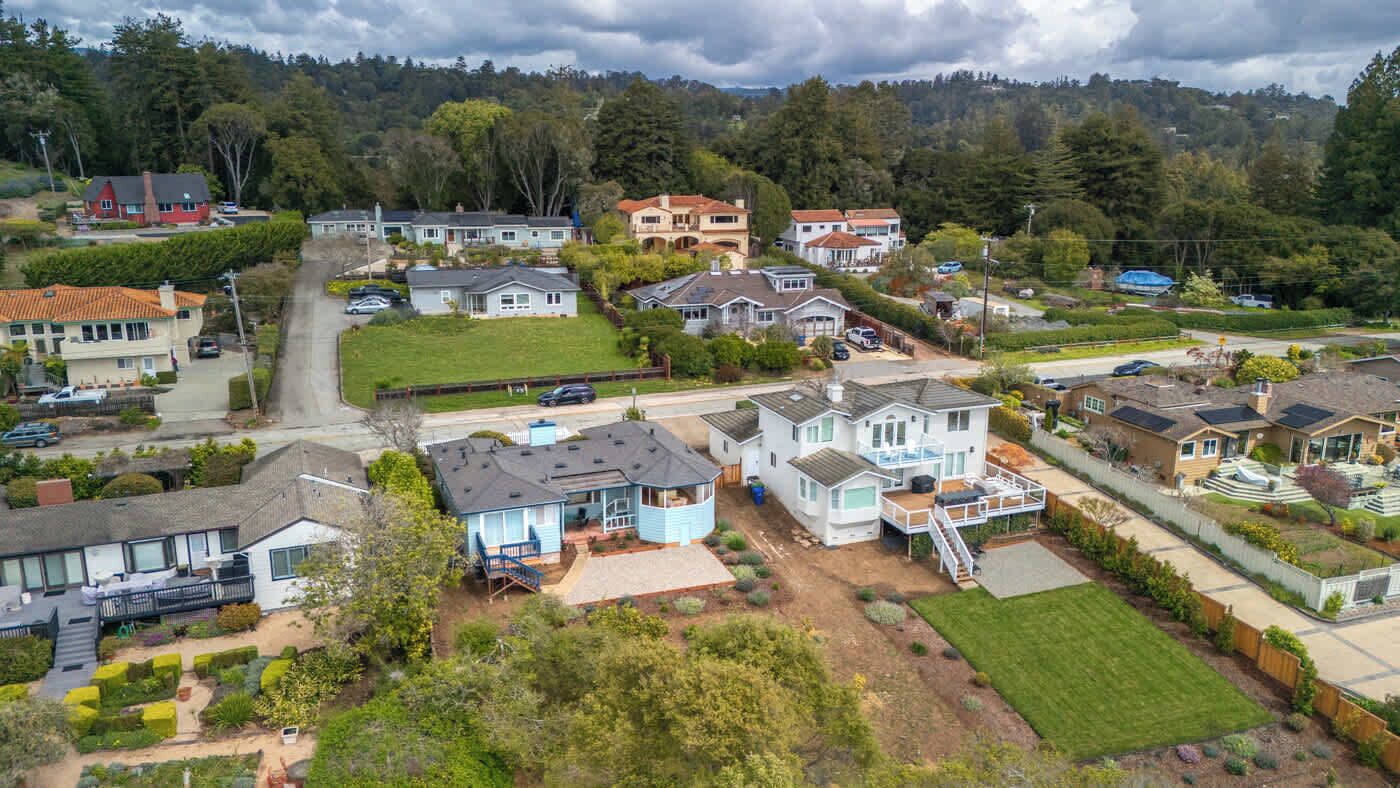 An aerial view of a residential area with houses, roads, and greenery.