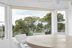 A room with a round table and white chairs, large windows with a view of trees and buildings. - 3 bedroom Aptos Home With Ocean View! (Aptos)