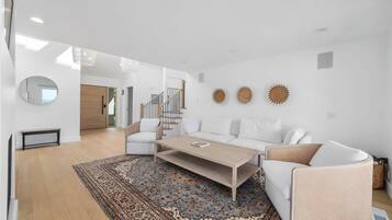 En moderne stue med sofa, sofabord og dekorative billeder på væggen.
