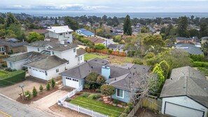 Un barrio residencial con casas, cerca viva blanca y vista al océano.