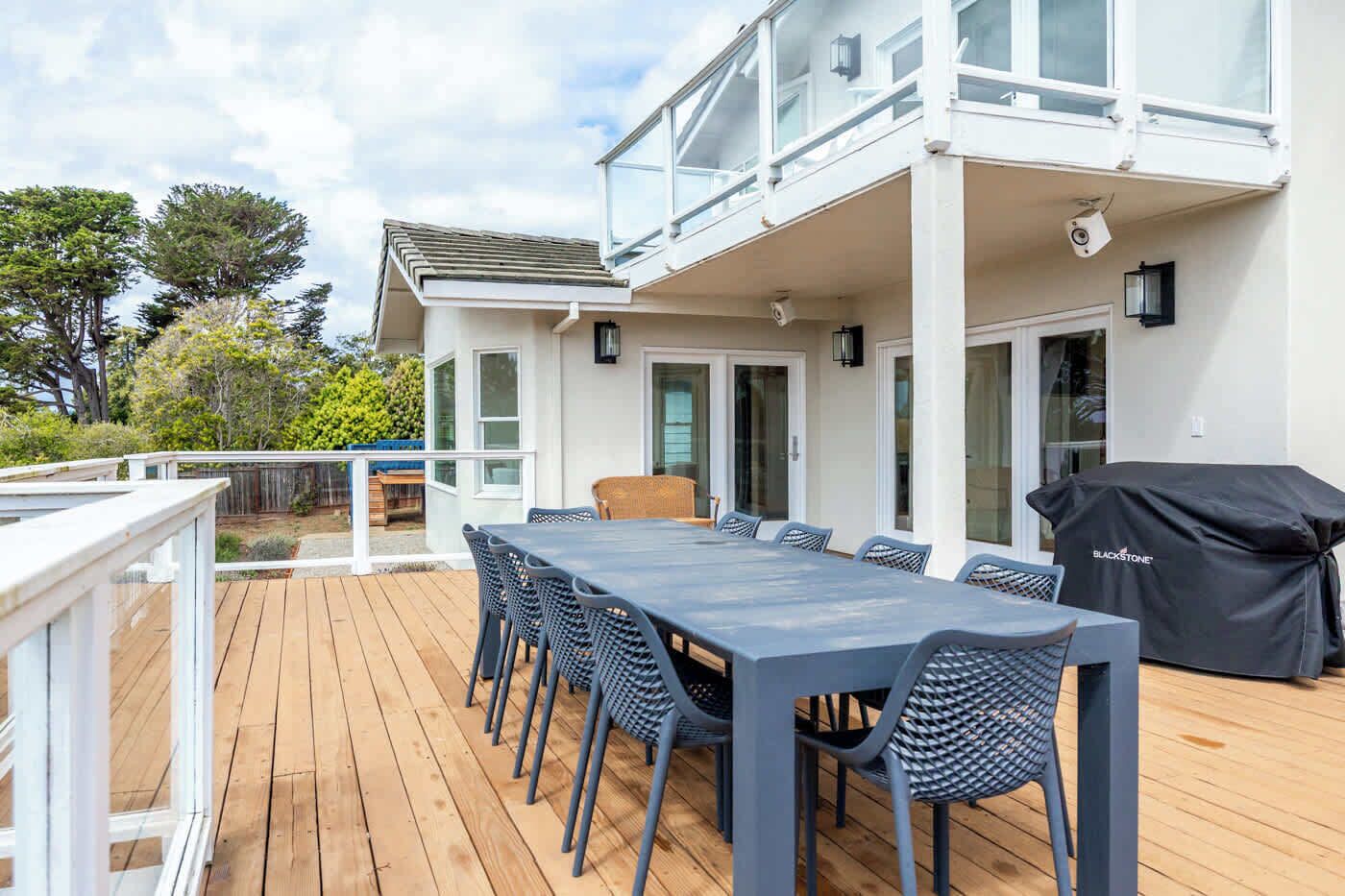 A deck with a table and chairs, a grill, and a view of the surrounding area.