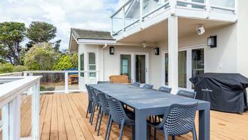 A deck with a table and chairs, a grill, and a view of the surrounding area.