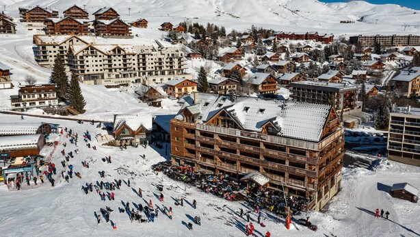 A ski resort with multiple wooden lodges, a ski lift, and a large building with balconies. - 6-person flat in a new residence on the snow front (LA TOUSSUIRE)