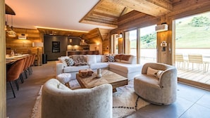 A spacious living area with a modern sofa, a wooden coffee table, and a fireplace. - 12-person flat with jacuzzi and sauna on the snow front (LA TOUSSUIRE)