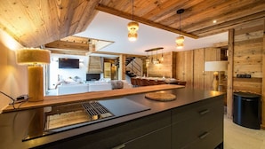 A modern kitchen with a wooden ceiling, a central island with a sink, and pendant lighting. - 12-person flat with jacuzzi and sauna on the snow front (LA TOUSSUIRE)