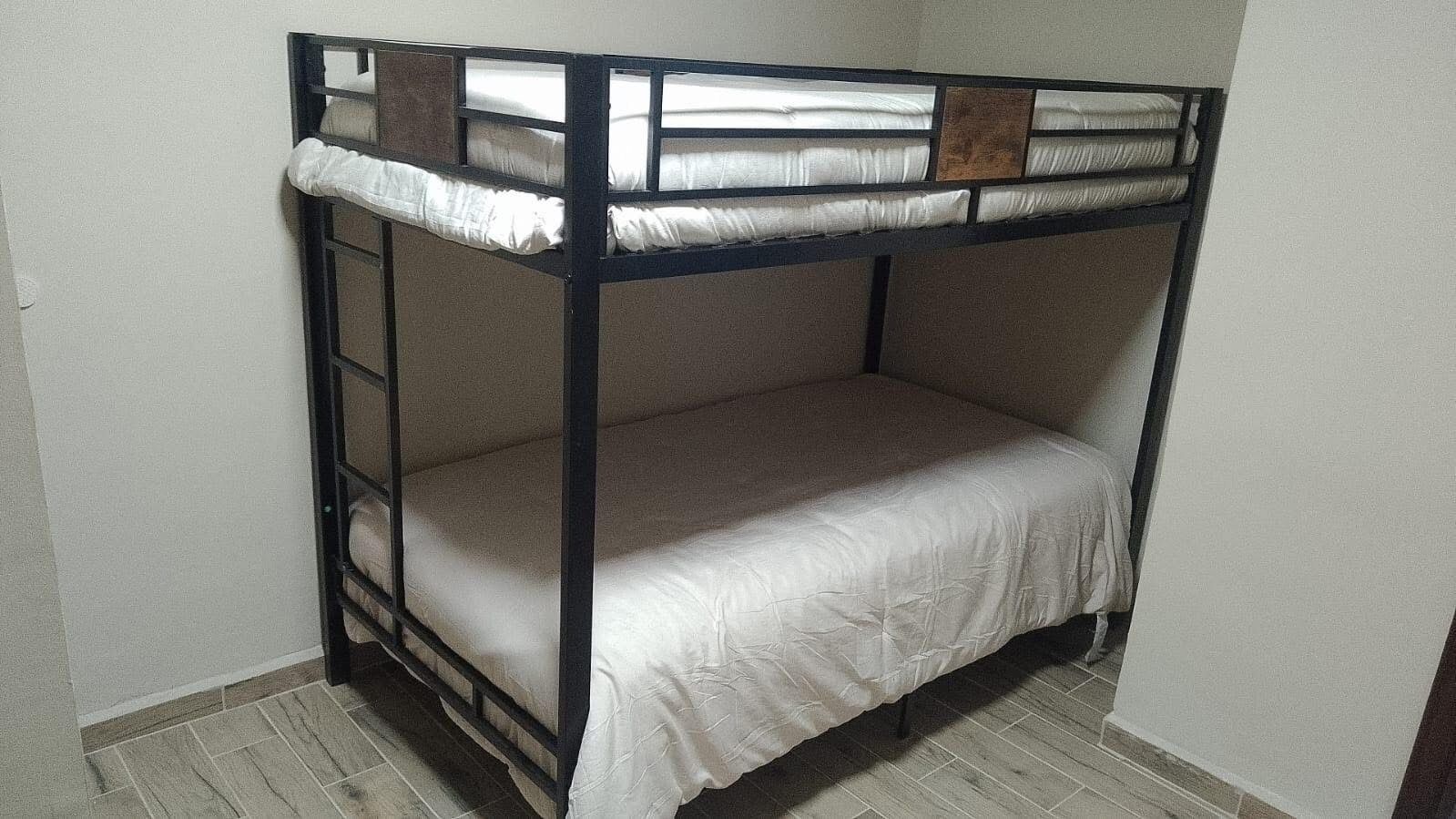 A bunk bed with a ladder, white bedding, and a wooden headboard.