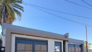 Un bâtiment moderne doté de deux grandes portes de garage, un ciel dégagé et un palmier en arrière-plan.