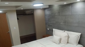 Une chambre à coucher comprenant un lit, des tables de chevet, une armoire et une tête de lit intégrée.