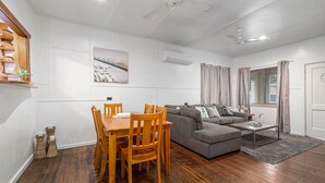 Ein modernes Wohnzimmer mit Esstisch, Holzsesseln, einem grauen Sofa und einem Couchtisch.
