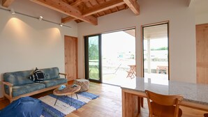 Un'ampia zona giorno con soffitto in legno, un divano, un tavolino da caffè e un tavolo da pranzo con sedie.