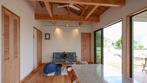 Un'ampia stanza con soffitto in legno, una grande finestra, un divano e un'area da pranzo.