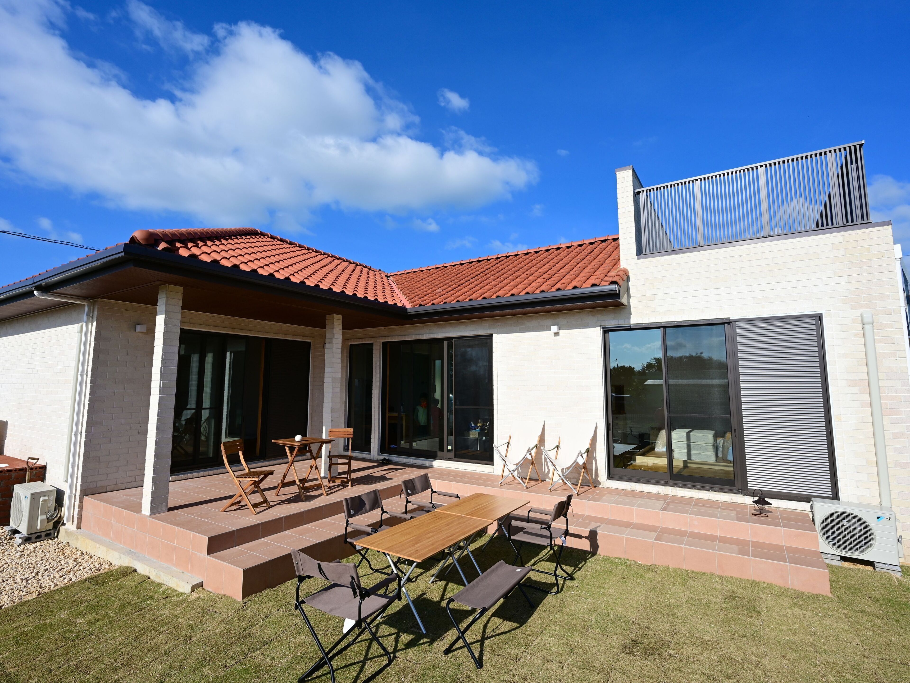 Uma casa moderna com um pátio, área de estar externa e uma grande porta de vidro deslizante.