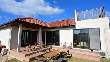 Uma casa moderna com um pátio, área de estar externa e uma grande porta de vidro deslizante.