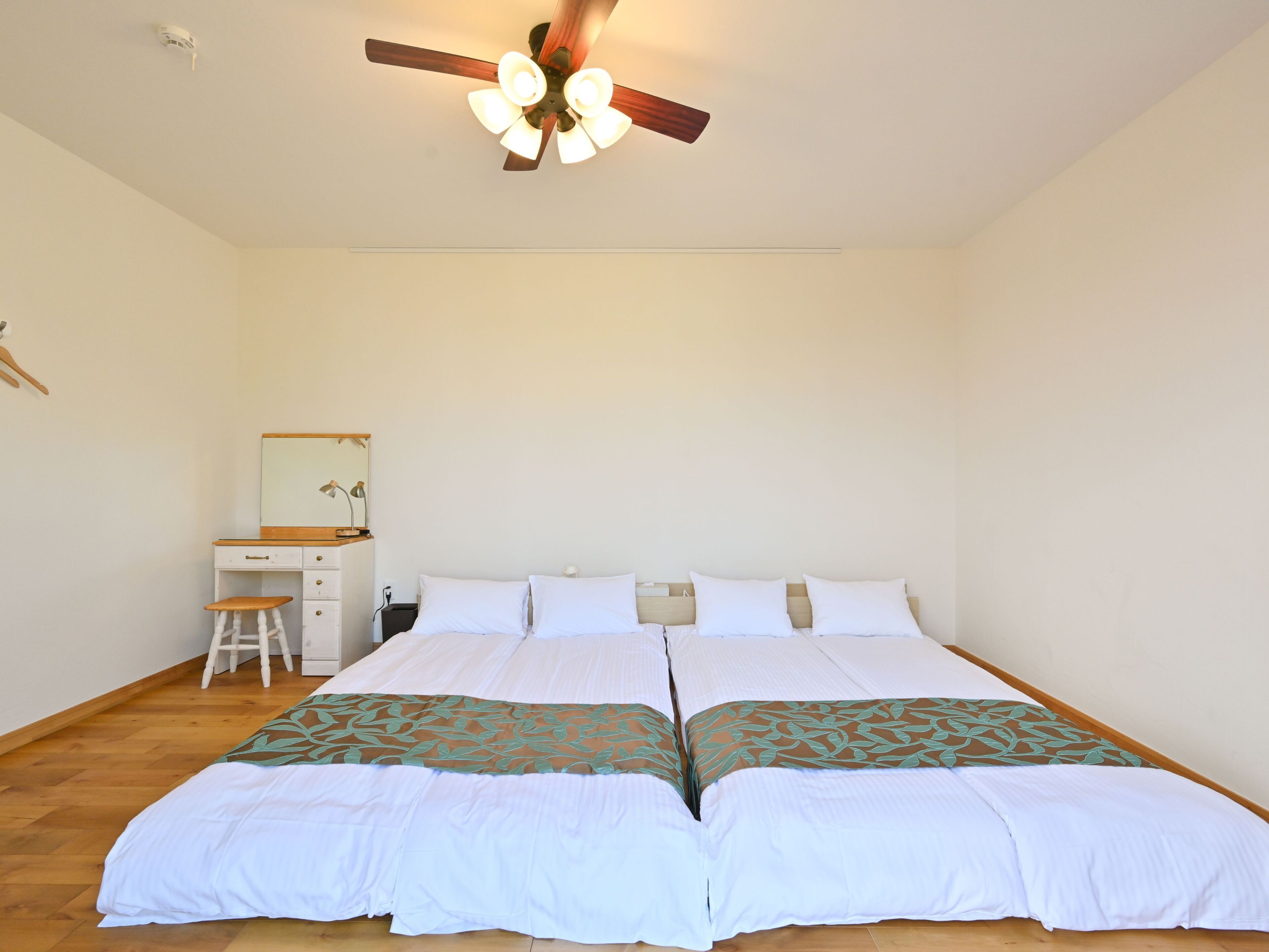 Ein Schlafzimmer mit einem Bett, einem Schreibtisch, einem Stuhl und einem Deckenventilator.
