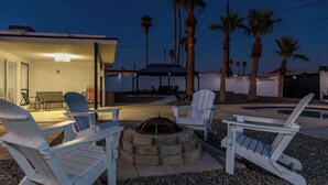 Un espace extérieur aménagé avec des chaises Adirondack, un foyer et une piscine.