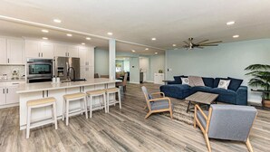 Une cuisine moderne avec des meubles blancs, un coin bar et un espace repas.