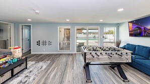 Un salon moderne avec un baby-foot, un canapé et une vue sur un pont.
