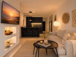A modern living room with a sofa, a coffee table, and a kitchen area in the background.