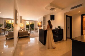 A modern living room with a sofa, a dining area, and a kitchen area with a black island.