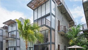 Un edifici modern de diverses plantes amb piscina, mobiliari exterior i vegetació abundant.