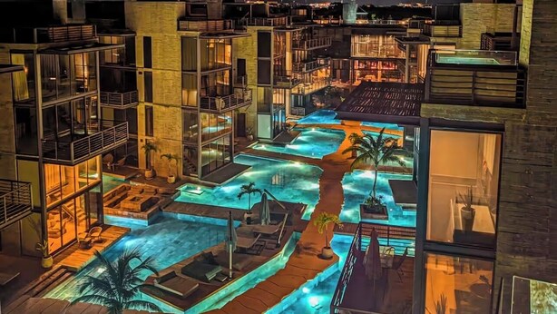 Hotel de diverses plantes amb zona de piscina al terrat, que inclou diverses piscines i gandules.