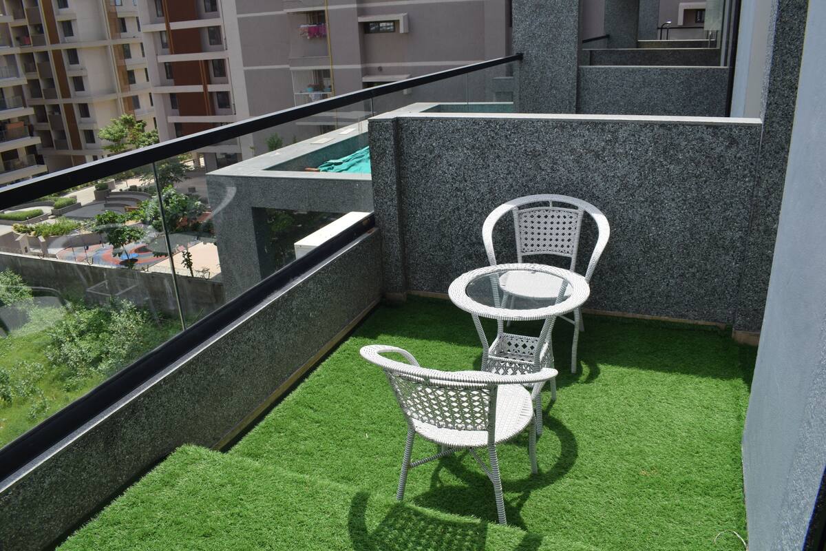 A balcony with artificial grass, two wicker chairs, and a small round table.