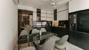 Une cuisine moderne aux couleurs noir et blanc, avec une table à manger en verre et un four encastré.