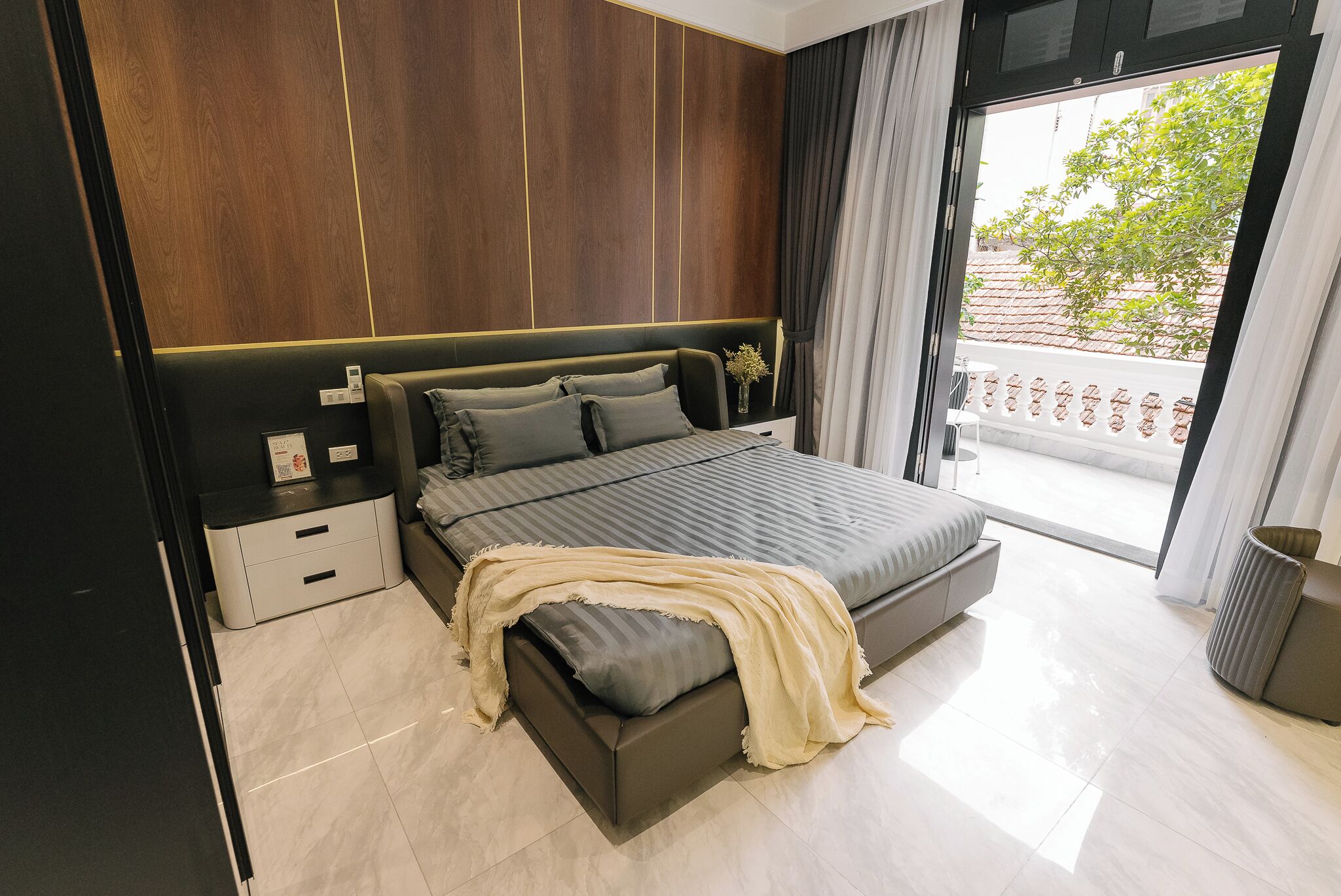 Ein modernes Schlafzimmer mit Bett, Nachttischen, Vorhängen an einem Fenster und Blick ins Freie.