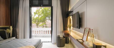 A modern bedroom with a bed, a bedside table, a TV mounted on the wall, and a view of the outdoors.