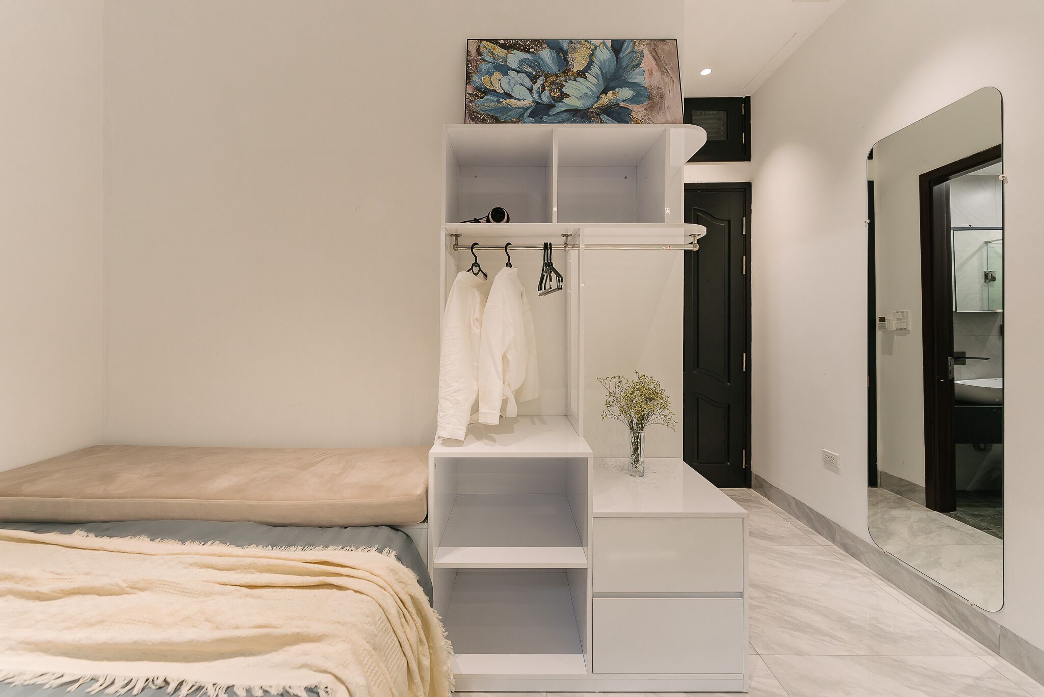 A modern bedroom with a built-in wardrobe, a bedside table, and a large mirror.