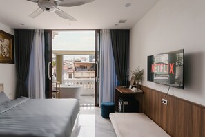 A hotel room with a bed, a desk, a TV mounted on the wall, and a balcony with curtains. - Tamundi Alley Homestay - Dragon Teeth - The Old Quarter Ha Noi (Hanoi)
