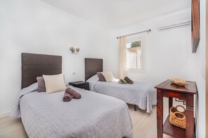 Ein Hotelzimmer mit zwei Betten, einem Nachttisch, einem Holztisch und einem Fenster mit Vorhängen.