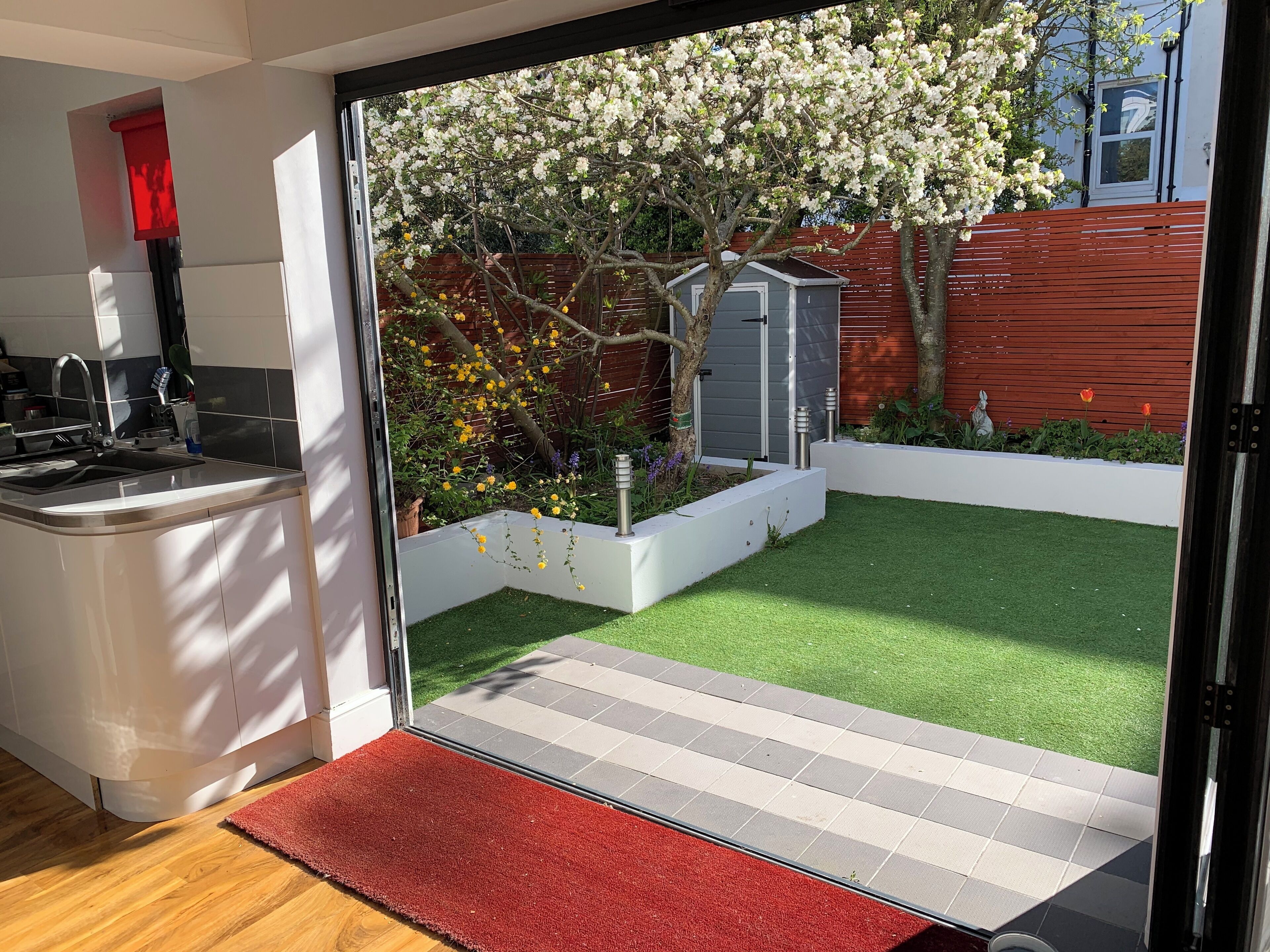 A modern kitchen with a built-in sink and a red mat at the entrance.