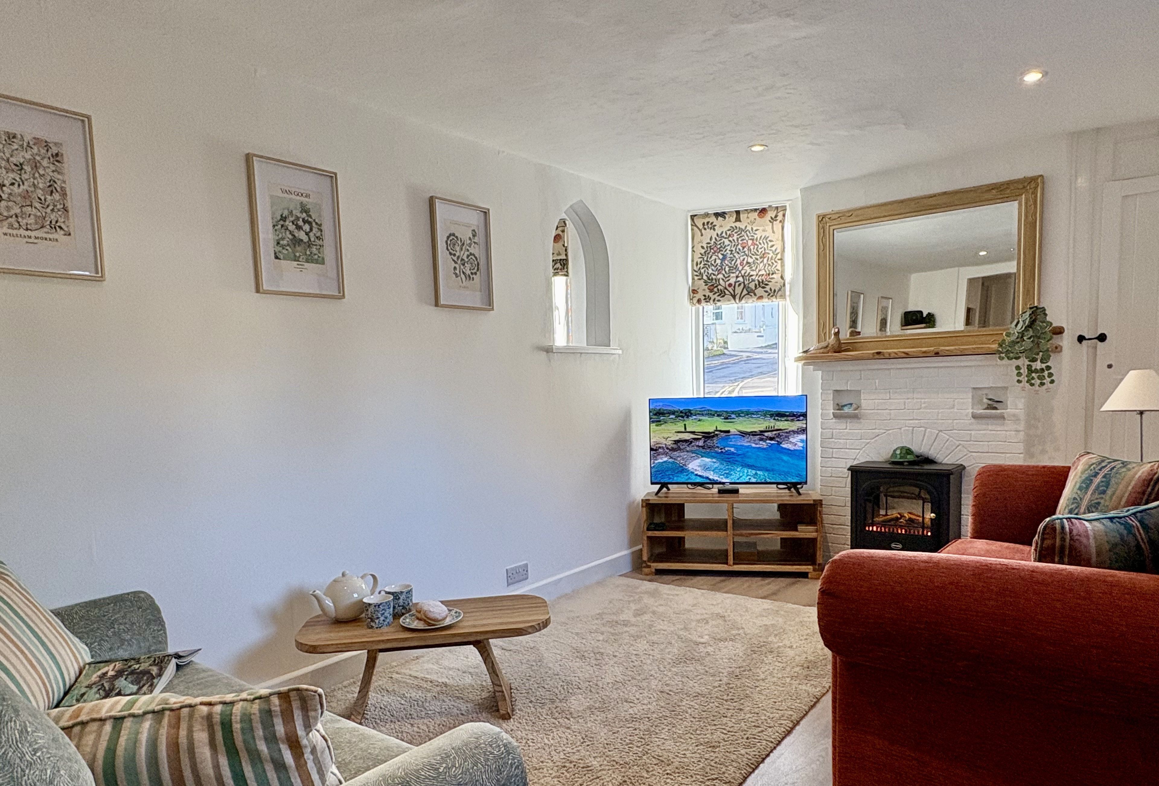 A living room with a fireplace, a television, and framed artwork on the wall.