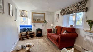 A cozy living room with a red sofa, a television, a fireplace, and a wooden coffee table.