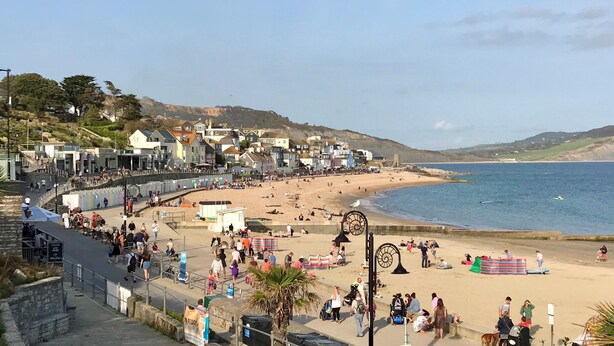 A coastal town with a beach, promenade, and buildings along the shore.