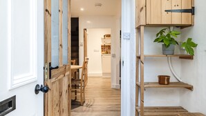 A hallway with wooden doors and shelves, leading to a dining area with a table and chairs.