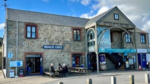 A stone building with a 'Beach Cafe' sign, 'Real Dairy Ice Cream' shop, and 'Charming Heritage Coast Centre' entrance. - Meads Cabin - Charmouth, Lyme Regis (Charmouth)