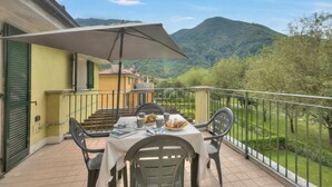 Un balcon avec une table dressée pour le petit-déjeuner, une chaise et un grand parasol.