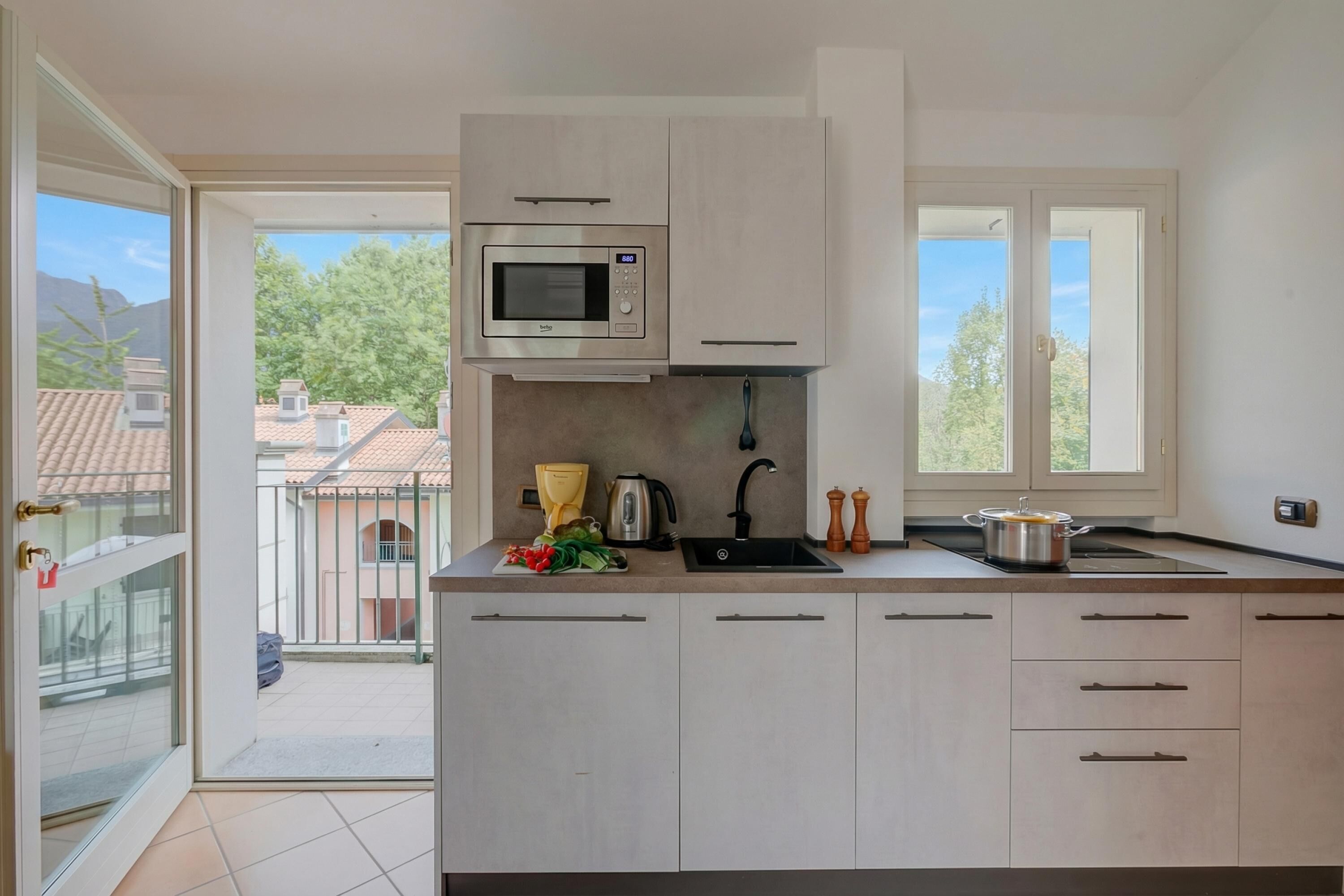 A modern kitchen with a built-in microwave, a sink, and a window overlooking a residential area.