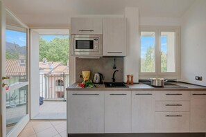 A modern kitchen with a built-in microwave, a sink, and a window overlooking a residential area. - Porto Letizia Orchidea 5, Porlezza, Italy (Porlezza)