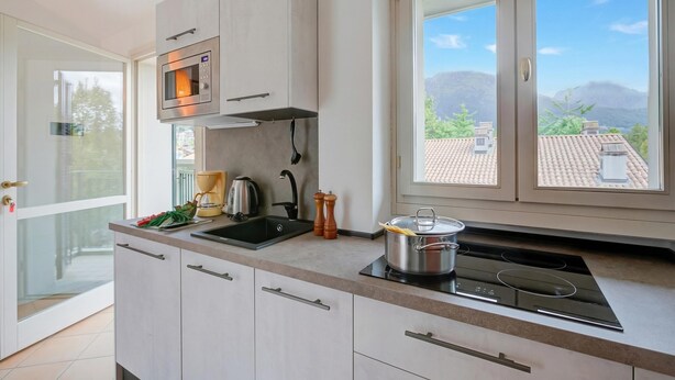 Une cuisine moderne dotée d’un four encastré, d’une plaque de cuisson et d’une grande fenêtre offrant une vue sur les montagnes.